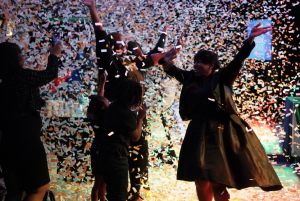 Group of people celebrating with confetti falling around them.
