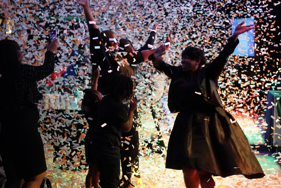 Group of people celebrating with confetti falling around them.