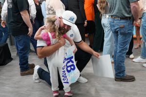A man in a hat hugging his young daughter.