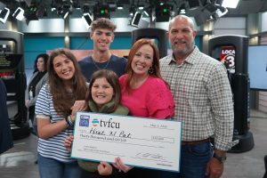 Family in a TV studio holding a large check.