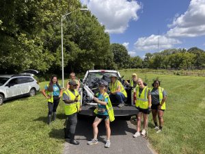 Volunteers pose by pickup truck with bags of trash and trash grabbers.