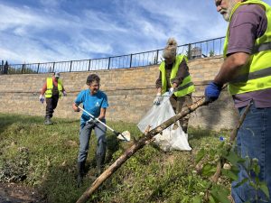 volunteers use trash grabbers to fill bags with trash on shoreline