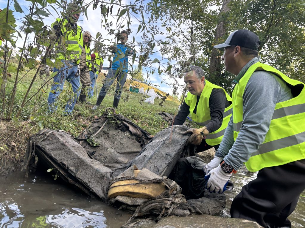 two men remove sofa from creek